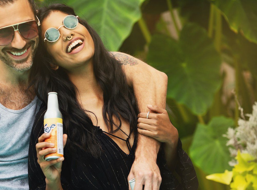 A man and woman are seen drinking medical marijuana from a bottle.